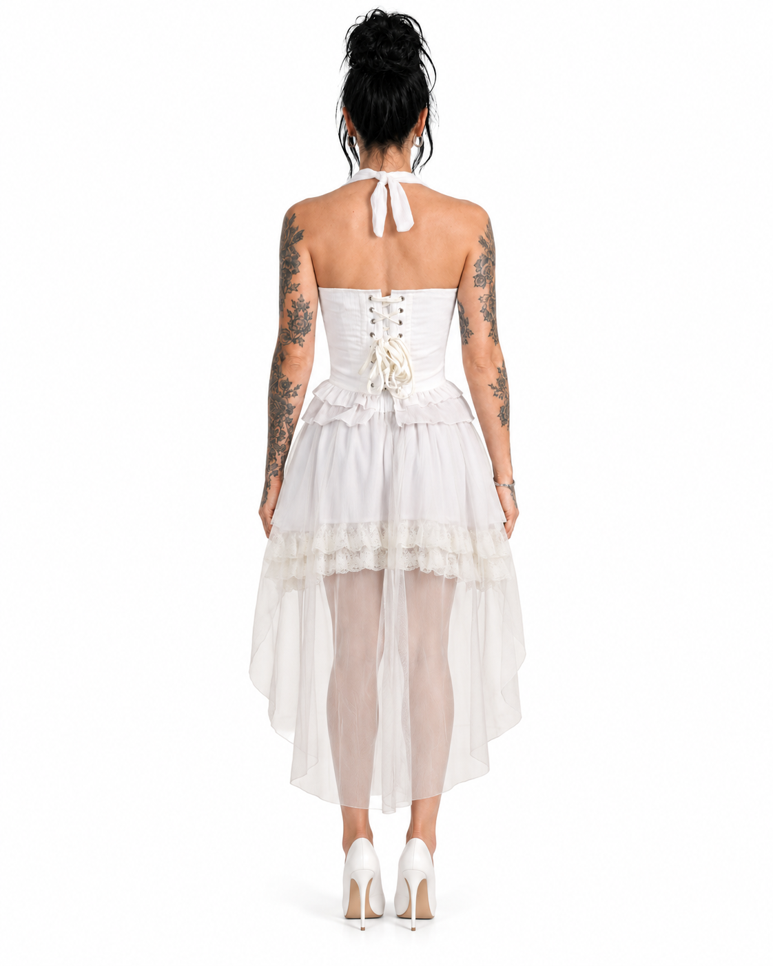 A woman modeling a white two-piece outfit consisting of a halter crop top with ruffle trim and a matching high-low tulle skirt with lace detailing