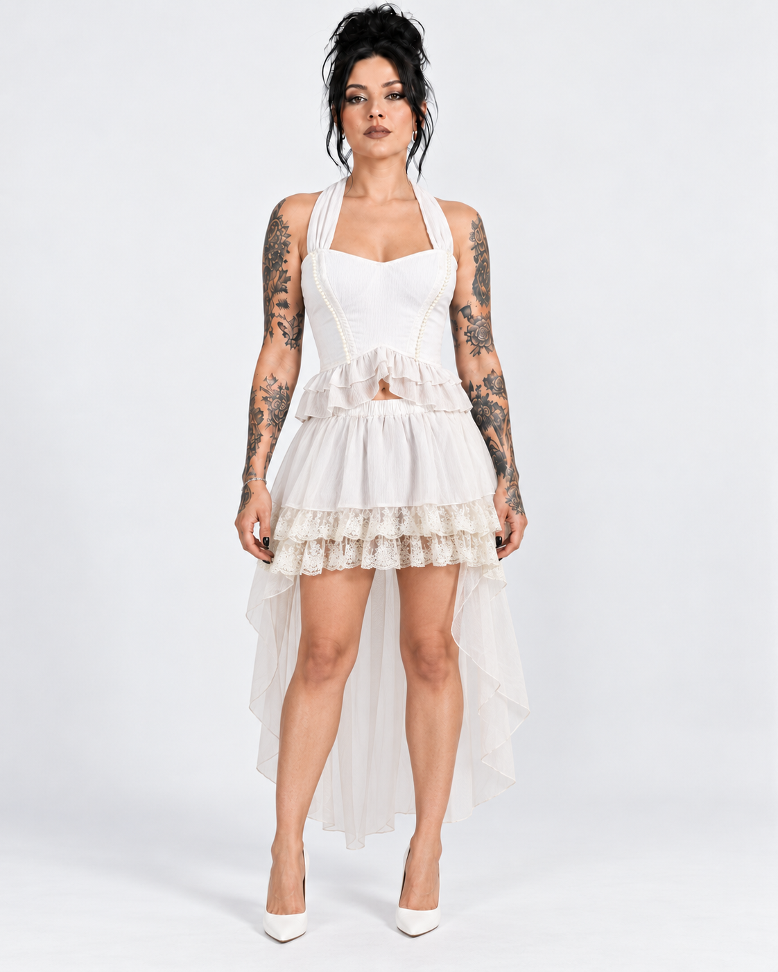 Tattooed model wearing a white pearl-trim halter corset with a layered lace high-low skirt.