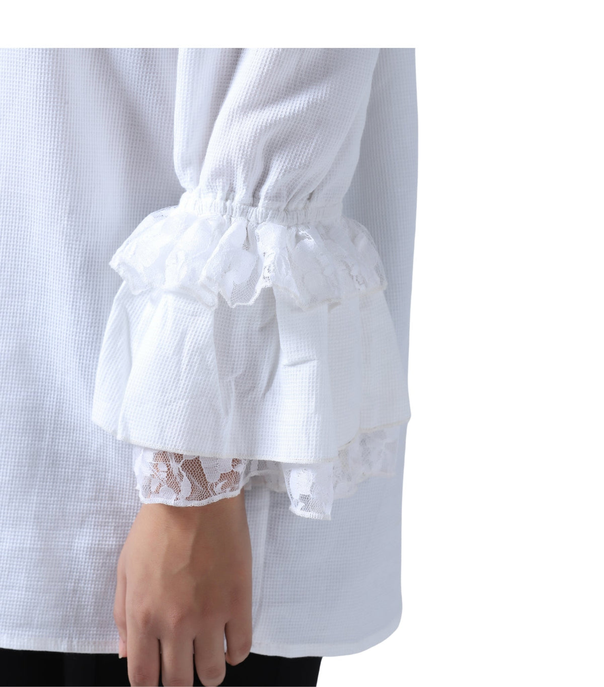 White long-sleeve blouse with a textured waffle fabric, elasticized gathered waist, and layered ruffled sleeves finished with lace trim, shown on a model against a white background.