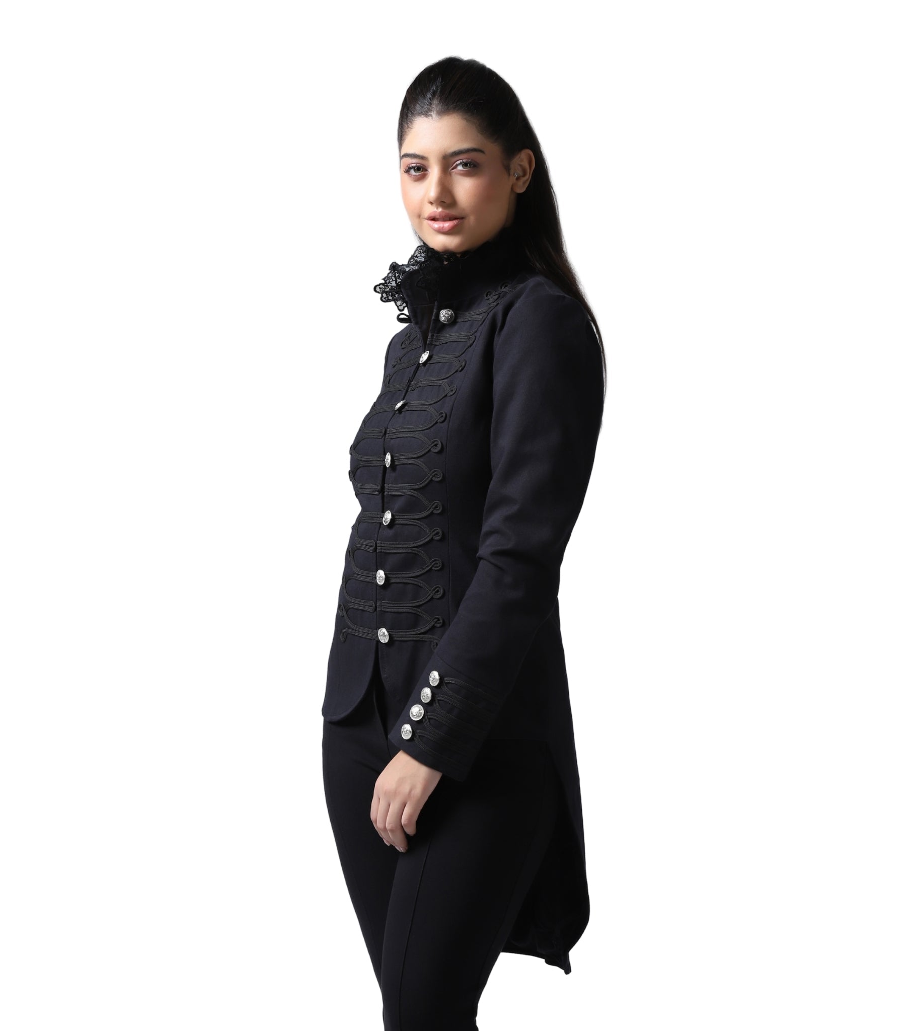 A woman modeling a black longline military-style jacket with ornate button details, a high ruffled collar, and matching black trousers against a plain white background.