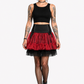 A model wearing gothic-style outfit featuring a black crop top, a black corset-style waistband, a red and black tiered tulle skirt, fishnet tights, and black platform boots, available for wholesale