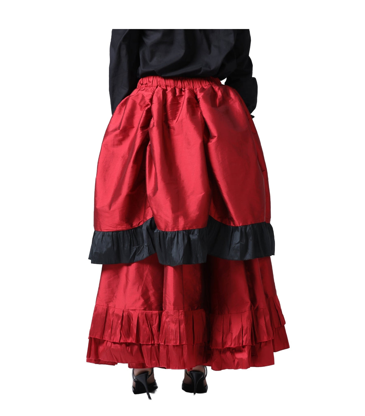 A red tiered skirt with black ruffle trim, shown on a model from the back against a white background.
