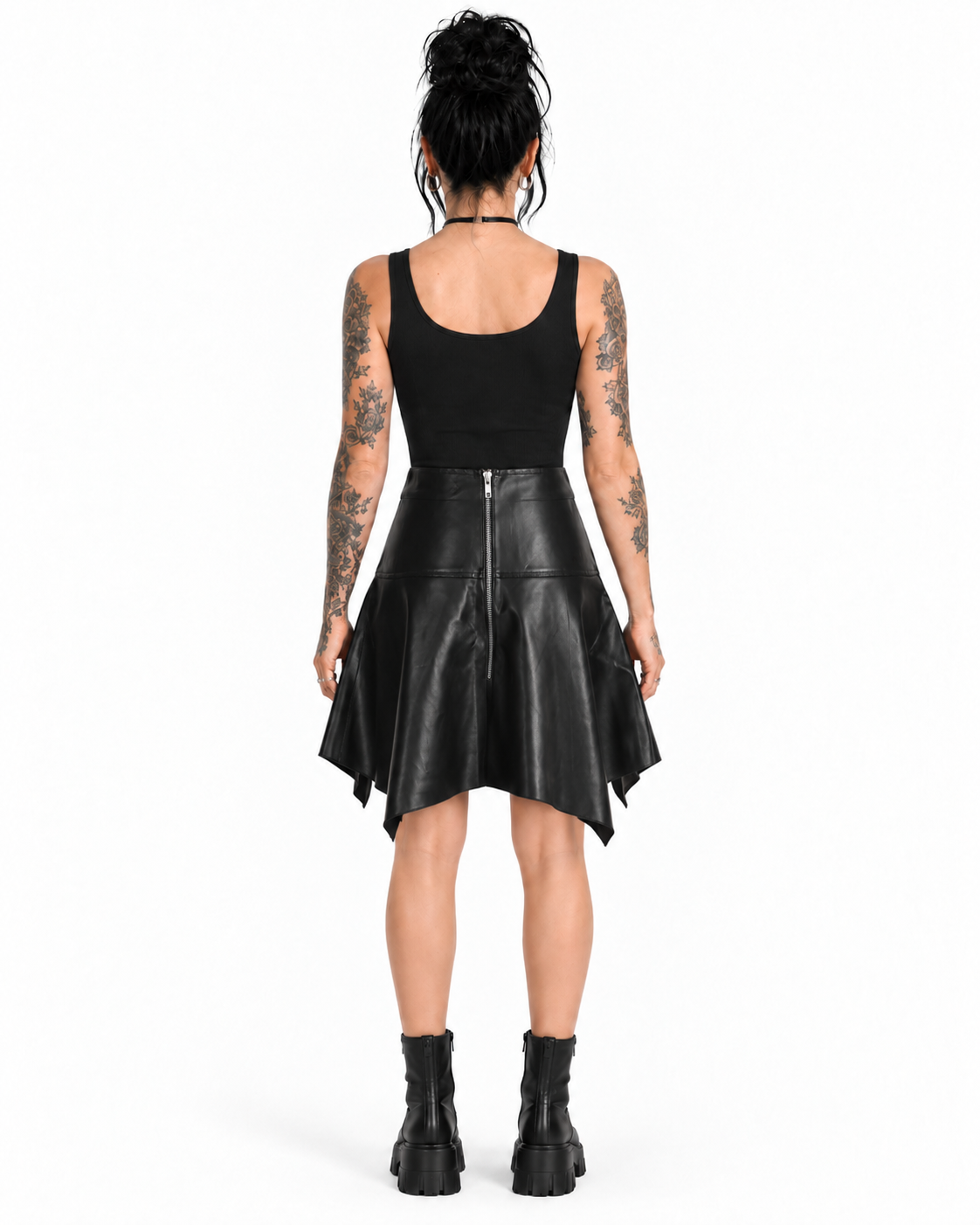 Back view of a model wearing a black PU asymmetrical skirt with a silver centre-back zipper and pointed hem.