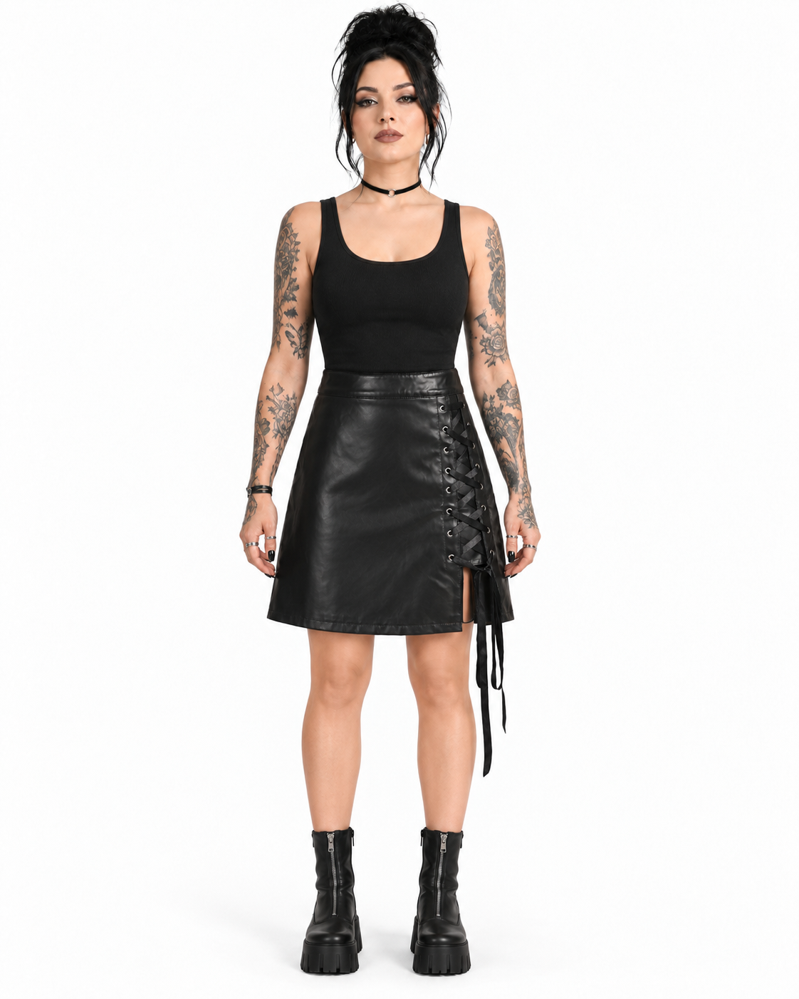 Front view of a model wearing a black PU A-line skirt with silver eyelets and side ribbon lacing.