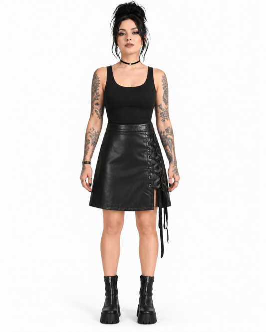 Front view of a model wearing a black PU A-line skirt with silver eyelets and side ribbon lacing.