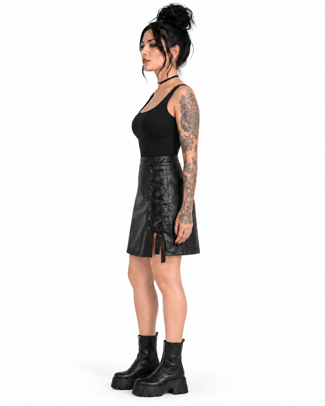 Side view of a tattooed model wearing a black PU Gothic skirt with visible eyelet lacing, side slit and tied ribbon ends.