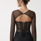  Back view of black dotted mesh corset top with a curved cut-out, upper fastening and adjustable black lacing.