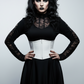 Woman wearing a black lace top and white corset against a dark background